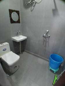 a bathroom with a toilet and a sink and a bucket at Guruji Homestay Near UPES Collage in Jhājra