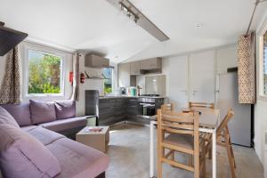 a living room with a purple couch and a table at Bungalow Cap Ferret Les Lodges 3 in Lège-Cap-Ferret +15 photos