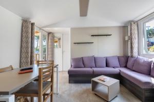 a living room with a purple couch and a table at Bungalow Cap Ferret Les Lodges 3 in Lège-Cap-Ferret