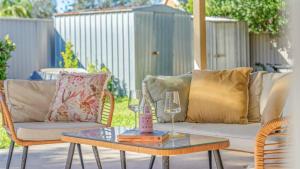 a patio with a couch and a table with wine glasses at Salt n Sand Beach house - 10min walk to Ocean - Idyllic coastal village in Ocean Shores +28 photos