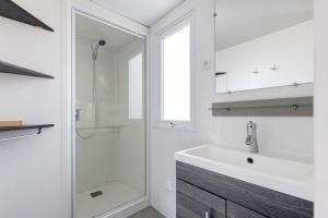 a white bathroom with a sink and a shower at Bungalow Cap Ferret Les Lodges 3 in Lège-Cap-Ferret