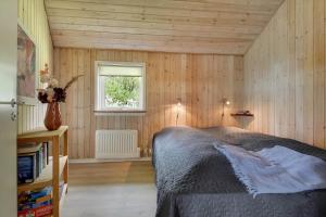 a bedroom with a bed in a room with wooden walls at C11323-Tarm-Brombaervej-8 in Tarm