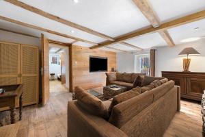 a living room with a couch and a tv at Chalet Le Hameau Tranquille in Courchevel
