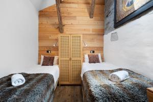 two beds in a room with wooden walls at Chalet Le Hameau Tranquille in Courchevel