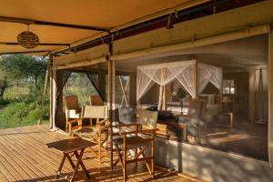 a porch of a safari tent with chairs and a table at Manya Luxury Camp in Serengeti +34 photos