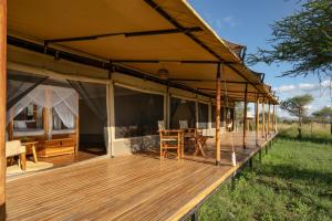 a deck of a tent with a table and chairs at Manya Luxury Camp in Serengeti