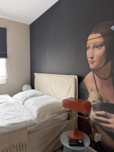 a bedroom with a painting of a woman holding a dog at VINCI apartment in Krakow