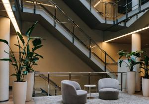 a lobby with two chairs and a staircase at WestCord Hotel Schylge in West-Terschelling