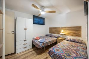 a bedroom with two beds and a ceiling fan at Sunwaves 2 - Casa Oasis in El Palmar