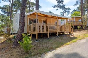 a cabin in the woods with a large deck at Bungalow Cap Ferret Les Lodges 2 in Lège-Cap-Ferret