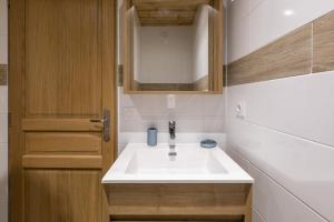 a bathroom with a white sink and a wooden door at Résidence La Forêt Du Praz - Courchevel 1850 in Courchevel