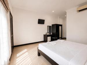 a bedroom with a white bed and a television at Champs Elysees Boutique Hotel in Phumĭ Réach Born (2)