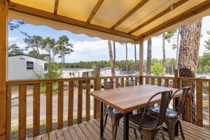 a wooden deck with a wooden table and chairs at Bungalow Cap Ferret Les Lodges 2 in Lège-Cap-Ferret