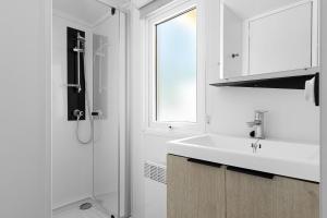 a white bathroom with a sink and a shower at Bungalow Cap Ferret Les Lodges 2 in Lège-Cap-Ferret