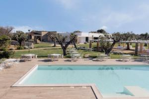 a swimming pool with tables and chairs in a yard at Masseria La Vecchia Lamia in San Vito dei Normanni