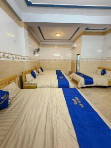 two beds in a room with blue and white sheets at Vân Tân Hotel in Kon Von Kla