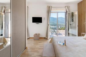 a bedroom with a bed and a balcony with a television at Douce Heure & Saveurs in Tavaco