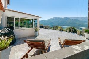 two chairs and a table on a patio with mountains at Douce Heure & Saveurs in Tavaco