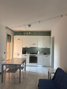 a kitchen with white cabinets and a table and chairs at La CASA DI ALE in Imola