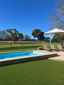 a swimming pool with two chairs and an umbrella at Marshden Estate in Stellenbosch