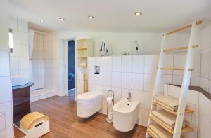 a white bathroom with a toilet and a sink at Strandwetter Dünenhotel in Borkum +29 photos