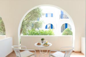 a table and chairs in a room with a window at Lagos Mare Hotel in Agios Prokopios
