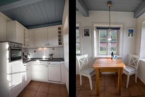 a kitchen with white cabinets and a wooden table at Haus Nordmarsch in Langeneß