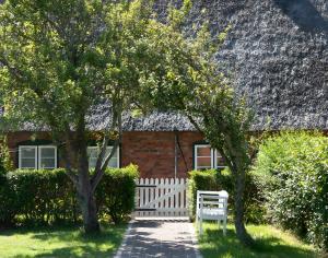 a brick house with a thatched roof and two trees at Haus Nordmarsch in Langeneß +19 photos