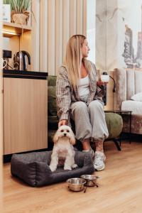 a woman sitting on a chair with a dog in a bed at Manhattan High Line Apart in Kyiv