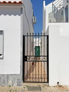 a black gate in a white building with a doorway at Casa Formosinha Cabanas Beach in Cabanas de Tavira