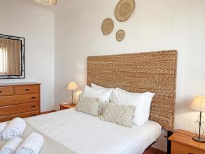 a bedroom with a bed with white sheets and pillows at Casa Formosinha Cabanas Beach in Cabanas de Tavira