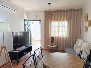 a living room with a table and a tv at Casa Formosinha Cabanas Beach in Cabanas de Tavira