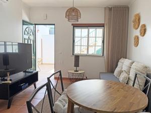 a living room with a table and a tv at Casa Formosinha Cabanas Beach in Cabanas de Tavira