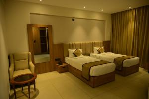 a hotel room with two beds and a chair at BHAVANIS Vista By ICON in Hosūr