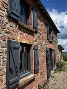 a brick building with black doors and windows at La jolie maison en grès rouge in Lagleygeolle