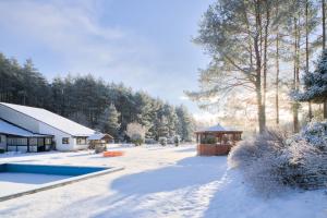 a yard covered in snow with a gazebo at Agroturystyka Uroczysko in Sianów