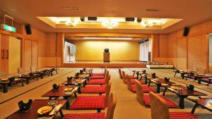 ein Esszimmer mit Tischen und Stühlen und einem Podium in der Unterkunft Livemax Resort Isawa Onsen in Fuefuki + 51 Fotos