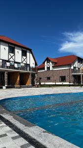 a swimming pool in front of a building at Семейные номера с ванной, кухней в Яхт Виллидж Чолпон-Ата in Cholpon-Ata