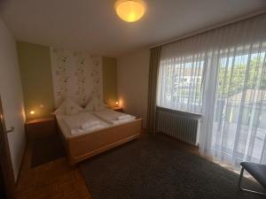 a bedroom with a bed and a large window at Pension Zimmermann in Unteruhldingen