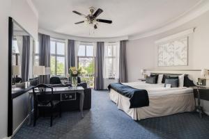 a bedroom with a bed and a desk and a ceiling fan at Crystal Plaza Hotel in Stockholm