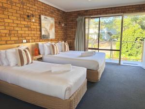 two beds in a room with a brick wall at Ocean View Motor Inn Merimbula in Merimbula +21 photos