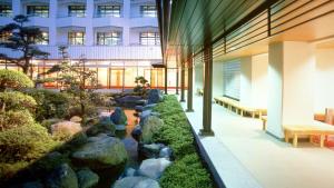 ein Gebäude mit einem Teich inmitten eines Gartens in der Unterkunft Livemax Resort Isawa Onsen in Fuefuki