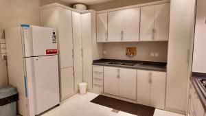 a kitchen with white cabinets and a white refrigerator at نزل ليلى الفندقية الفاخرة luxury in Abha