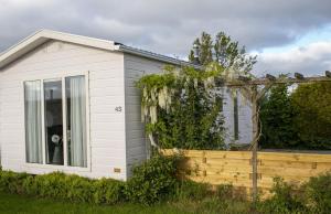a small white house with a wooden fence at Chalet nr 43 in Molkwerum +5 photos