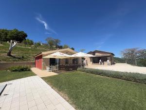 a building with tables and umbrellas in a yard at Villa Elena in San Severino Marche
