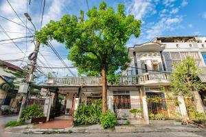 a tree in front of a white building at Di Mo homestay Citadel Conner in Thôn Kim Long (1)