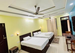 a bedroom with two beds and a ceiling fan at Hotel Almora Palace in Almora