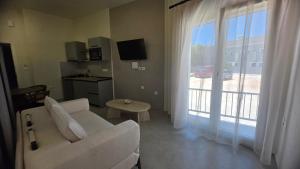 a living room with a white couch and a large window at Inos Boutique Apartments in Skala Prinou