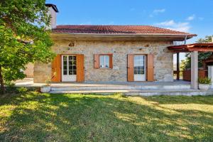 a small stone house with orange doors and a yard at Casa Na Aldeia in Arões