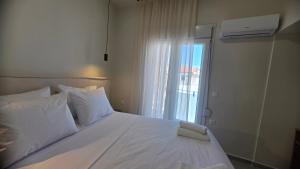 a bedroom with a white bed with a window at Inos Boutique Apartments in Skala Prinou